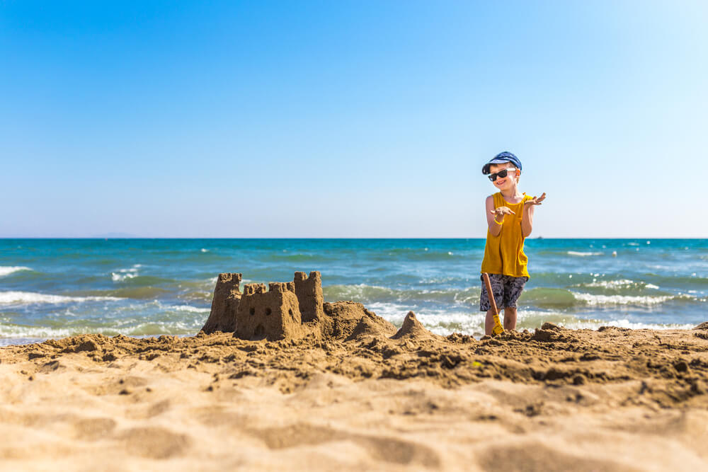 A kid making a sandcastle on a Kill Devil Hills beach.