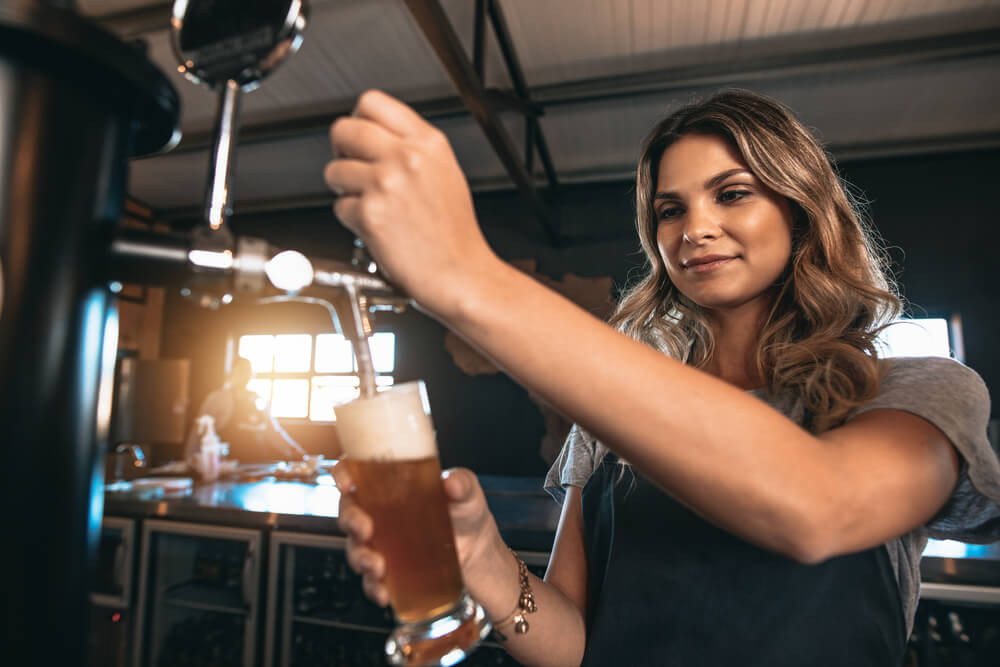 A photo of a woman pouring a beer at one of the breweries in the Outer Banks.